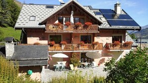 Eine zweistöckige Chalet mit Balkon, Sitzgelegenheit im Freien und Solaranlage.