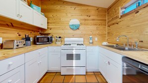 Une cuisine moderne avec des murs en bois, des armoires blanches, une cuisinière en acier inoxydable et un lave-vaisselle.