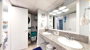 A bathroom with two sinks, a large mirror, and a shower.