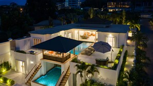 Ett modernt hus med en swimmingpool, utomhusmöbler och en täckt uteplats.