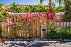 A wooden gate with a house number 1330, surrounded by lush greenery and flowering plants.