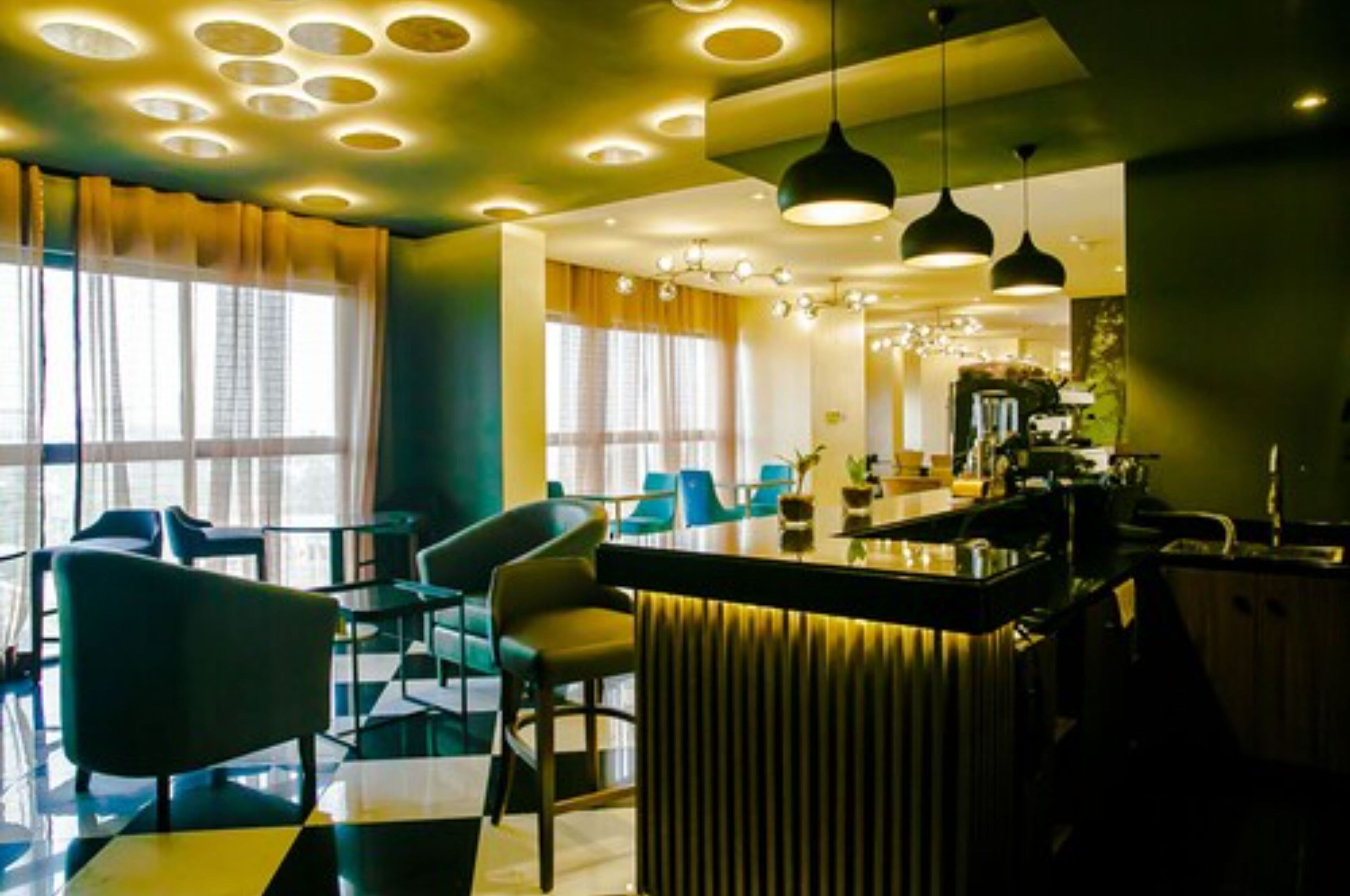 A modern hotel lobby with a bar area, seating, and a view of the cityscape.