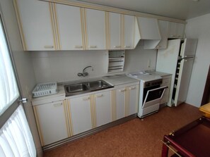 Een koelkast, een microgolfoven, een oven, kookgerei, borden en bestek