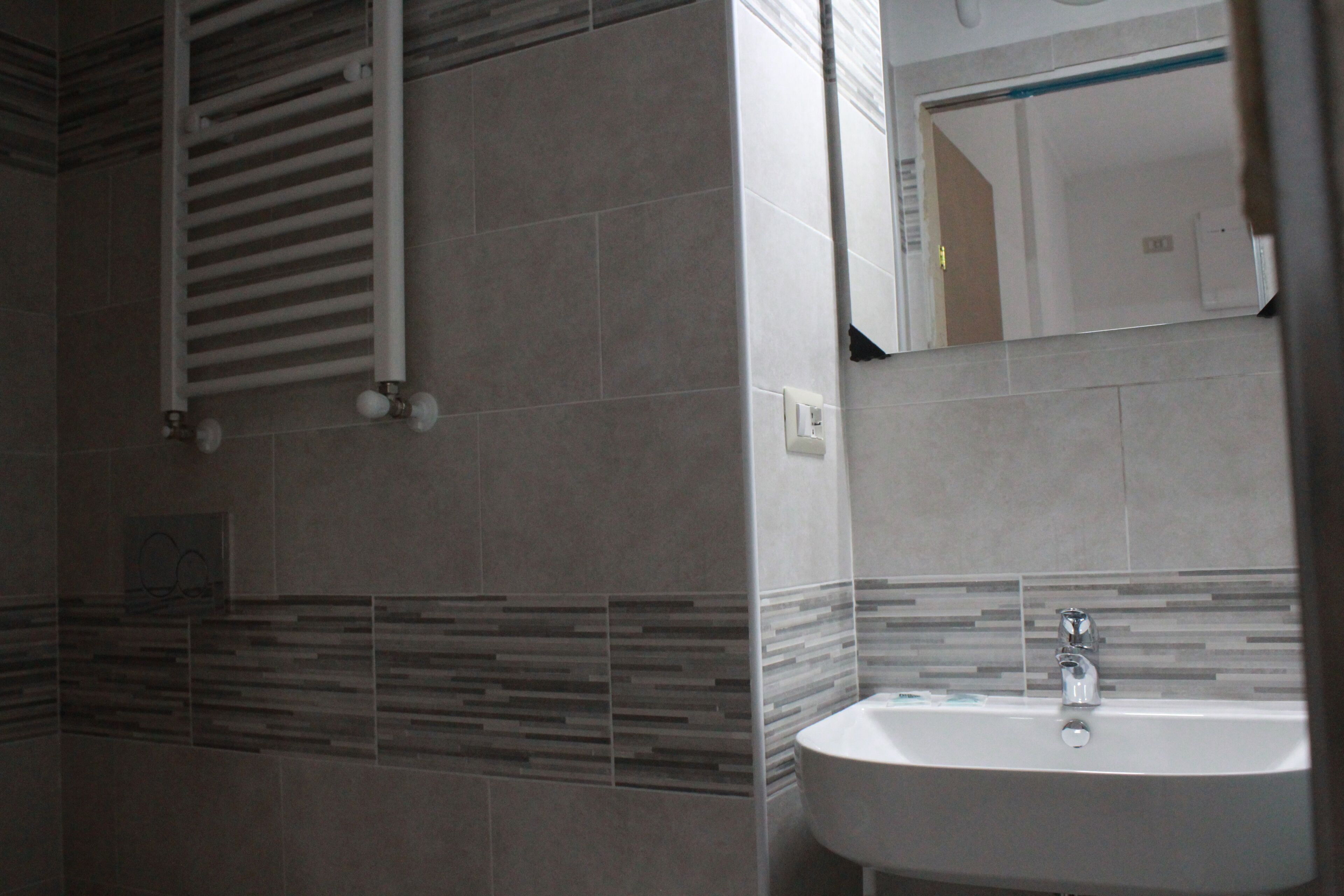 Une salle de bain avec un lavabo blanc, un porte-serviettes et un miroir.