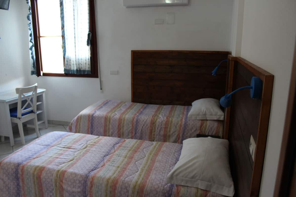 A bedroom with two beds, a wooden headboard, a desk, and a chair.