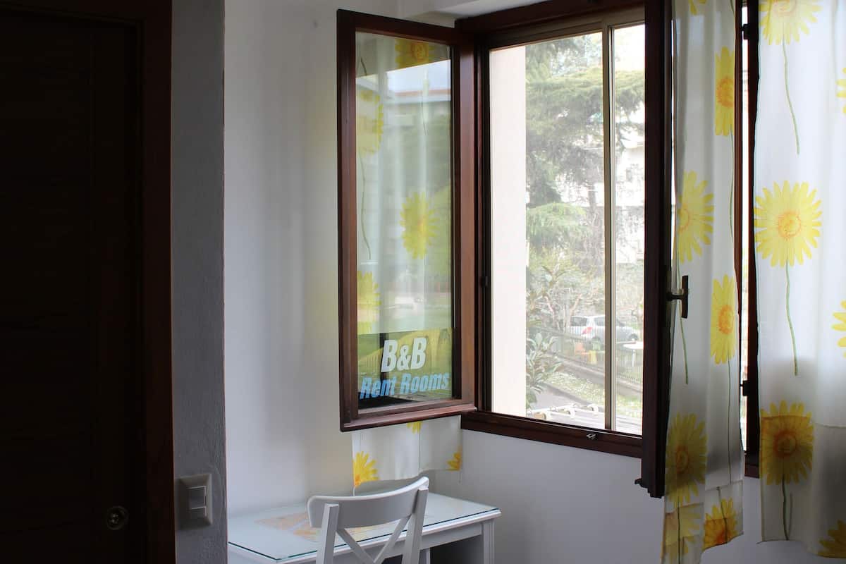 A room with two beds, a desk, and a window with curtains.