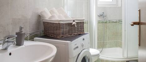 Un baño moderno con lavamanos, lavadora y ducha.