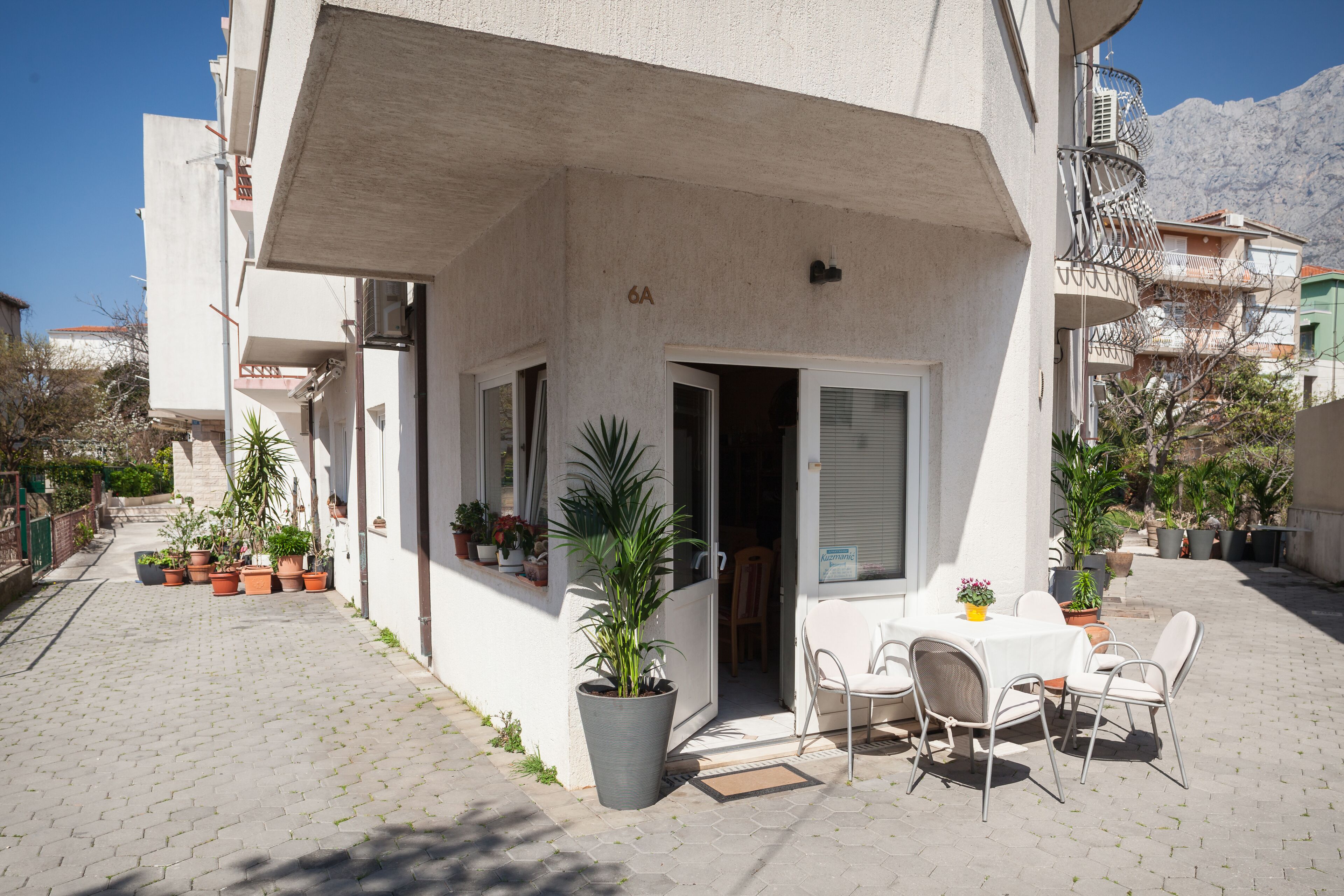 A courtyard with a table and chairs, potted plants, and a building entrance.