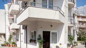 Un edificio de varios pisos con balcones, plantas en macetas y mobiliario exterior.