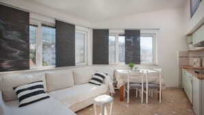 Una cocina moderna con comedor, ventanas amplias y un sofá blanco con almohadones a rayas.
