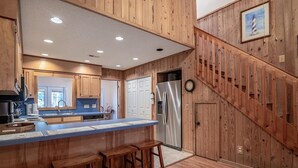A kitchen with wooden paneling, a stainless steel refrigerator, and a wooden staircase. - A Some Place Special Minutes to Beach Sleeps 10 (Pawleys Island)