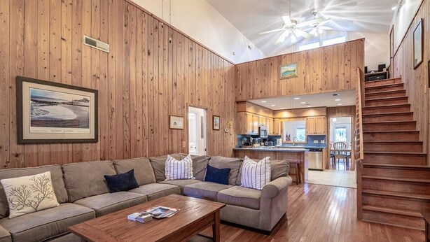 A spacious living area with a large sectional sofa, a wooden coffee table, and a kitchen in the background. - A Some Place Special Minutes to Beach Sleeps 10 (Pawleys Island)