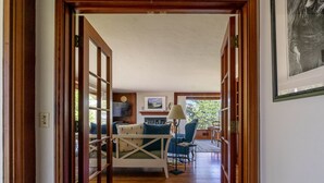 A hallway leading to a dining area with a white table and blue chairs, wooden flooring, and a framed picture on the wall. - Fourth Tee - Pacific Grove House - Ocean/Golf View (Pacific Grove)