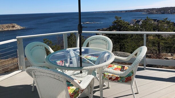 A balcony with a glass table and white wicker chairs, overlooking a coastal view. - The View: The Name Says It All (Rockport)