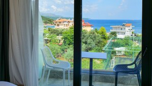 A hotel room with a balcony, a bed, a table, and two chairs. - Hotel Alexander (Ksamil)