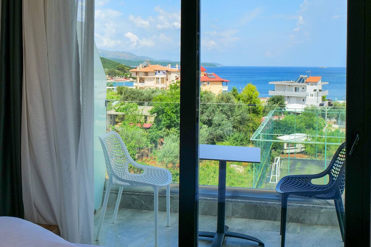 Una habitación de hotel con balcón, una cama, una mesa y dos sillas.