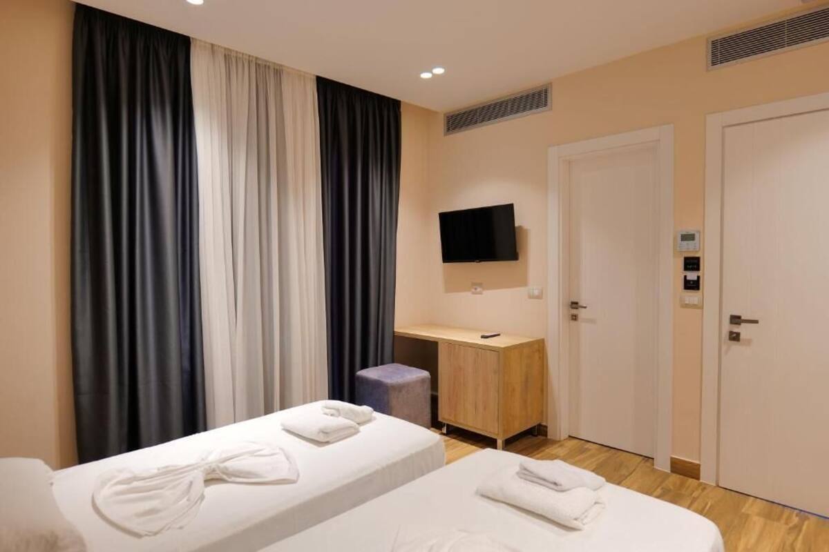 Una habitación de hotel con dos camas, un escritorio, un televisor y una puerta.