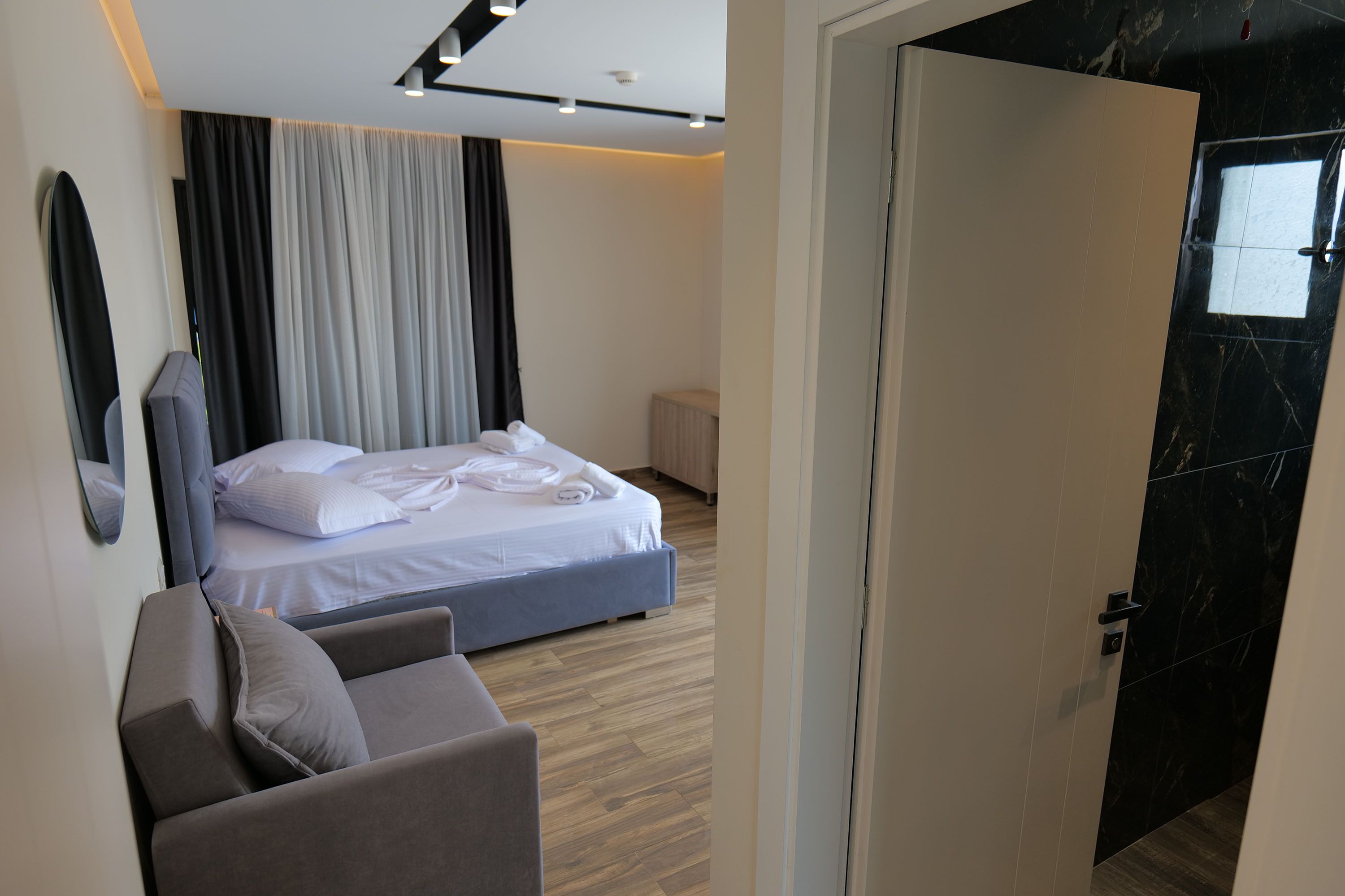 Ein modernes Hotelzimmer mit einem Bett, einer Sitzecke und einer Tür zu einem anderen Raum.