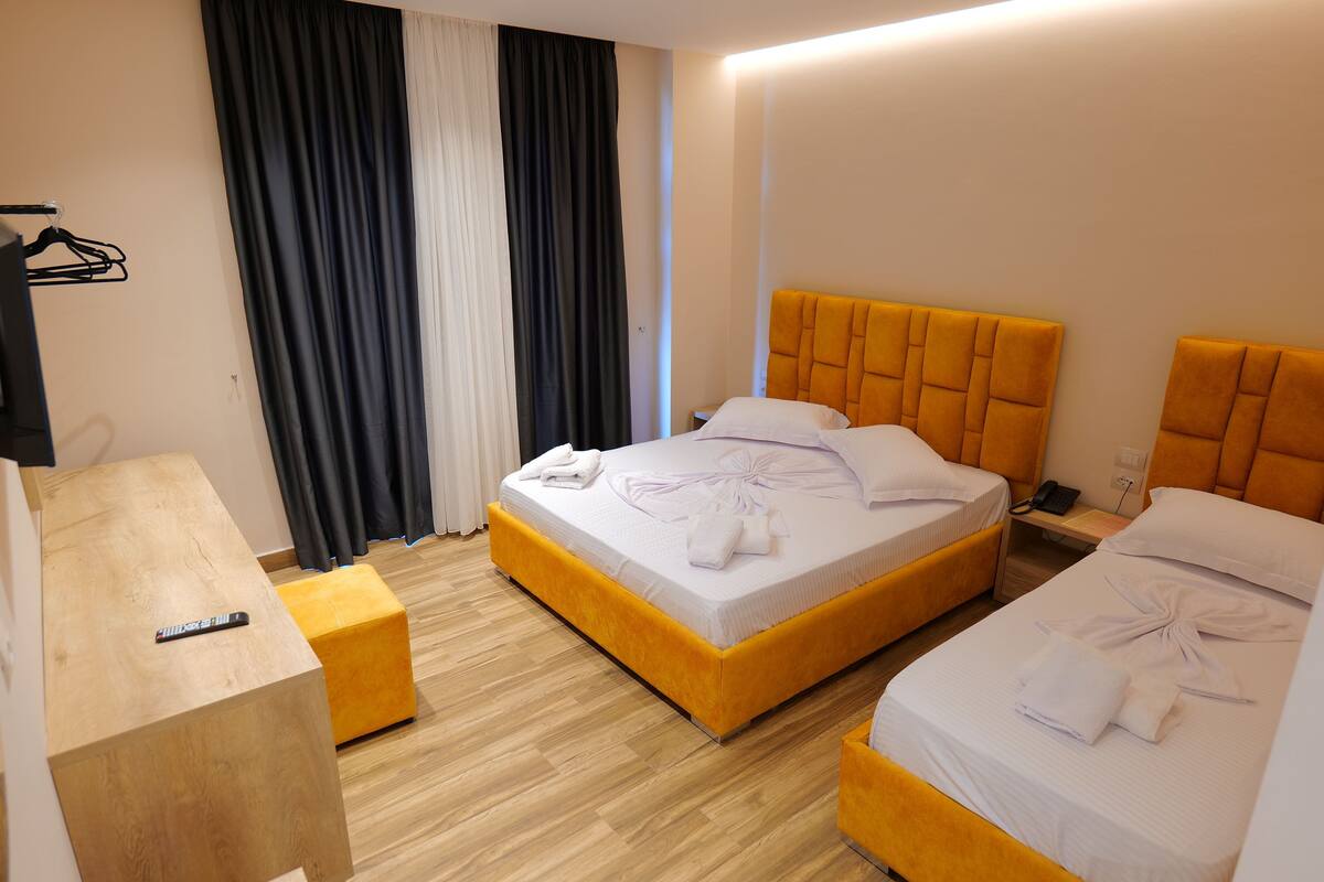 Habitación de hotel con dos camas, un escritorio de madera y un perchero.