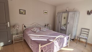 Ein Schlafzimmer mit einem Bett, einem Schrank, einem Sessel und einem Nachttisch.