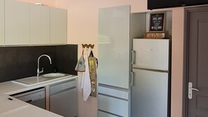 Eine kompakte Küche mit integriertem Geschirrspüler, Kühlschrank und Mikrowelle.