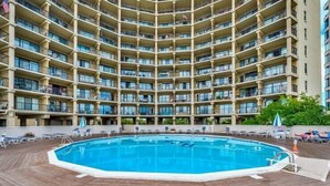 A multi-story hotel with a central swimming pool surrounded by lounge chairs and umbrellas. - High Point South 1C-Oceanfront 112th St, WIFI, Pool, Elev, W/D, AC (Ocean City)