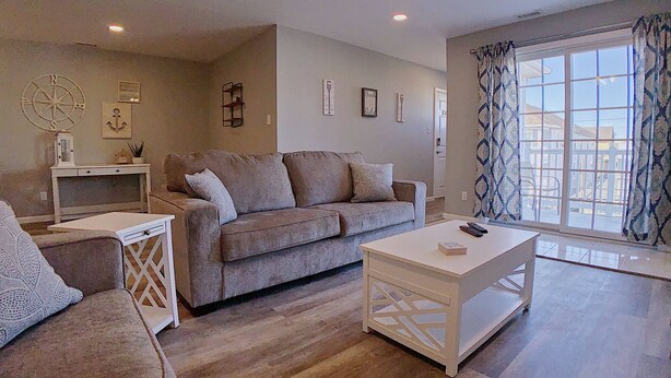 A living room with a sofa, a coffee table, and a TV. There is a window with curtains and a ceiling fan. - Stunning Renovations, Top Floor Views, and less than 2 Blocks to the Beach! (Wildwood)