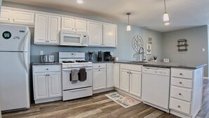 A modern kitchen with white cabinets, a microwave, stove, and a dishwasher. - Stunning Renovations, Top Floor Views, and less than 2 Blocks to the Beach! (Wildwood)