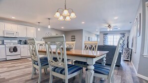 A modern kitchen with white cabinets, a wooden dining table, and blue-striped chairs. - Stunning Renovations, Top Floor Views, and less than 2 Blocks to the Beach! (Wildwood)