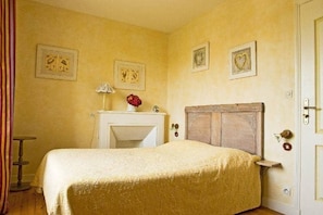 A bedroom with a bed, a nightstand, a lamp, and a door.