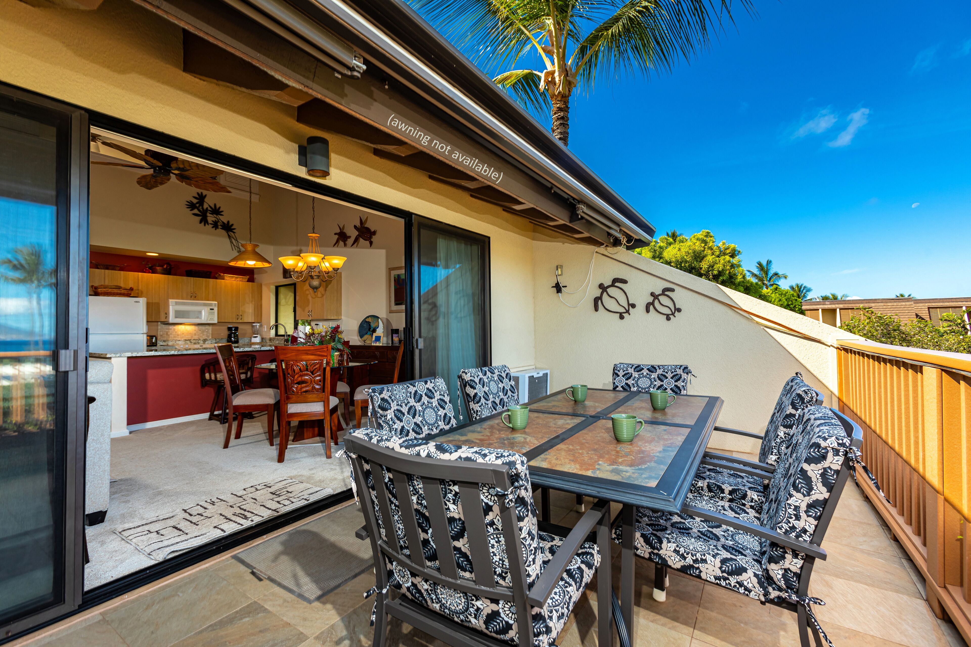 Un patio exterior con una mesa y sillas de comedor, un ventilador de techo y vistas a la cocina y la zona de la piscina.