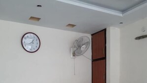 Een vergaderruimte met een houten tafel, een klok en een ventilator aan de muur.