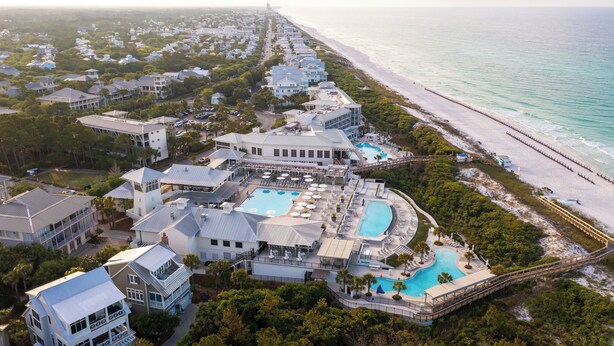 An aerial view of a coastal resort with multiple buildings, a large central pool, and a beach. - Chic Cottage 2 Blocks to Dragonfly Pool. With an LSV, Bikes, and More (Santa Rosa Beach)