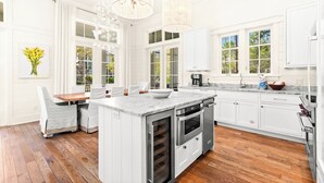 A spacious kitchen with a central island, white cabinetry, and a large window providing natural light. - Chic Cottage 2 Blocks to Dragonfly Pool. With an LSV, Bikes, and More (Santa Rosa Beach)