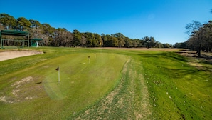 Un parcours de golf avec un gazon bien entretenu, des bunkers de sable et un ciel d’un bleu éclatant.