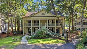 A two-story house with a front porch, a staircase leading to the entrance, and a well-maintained lawn.