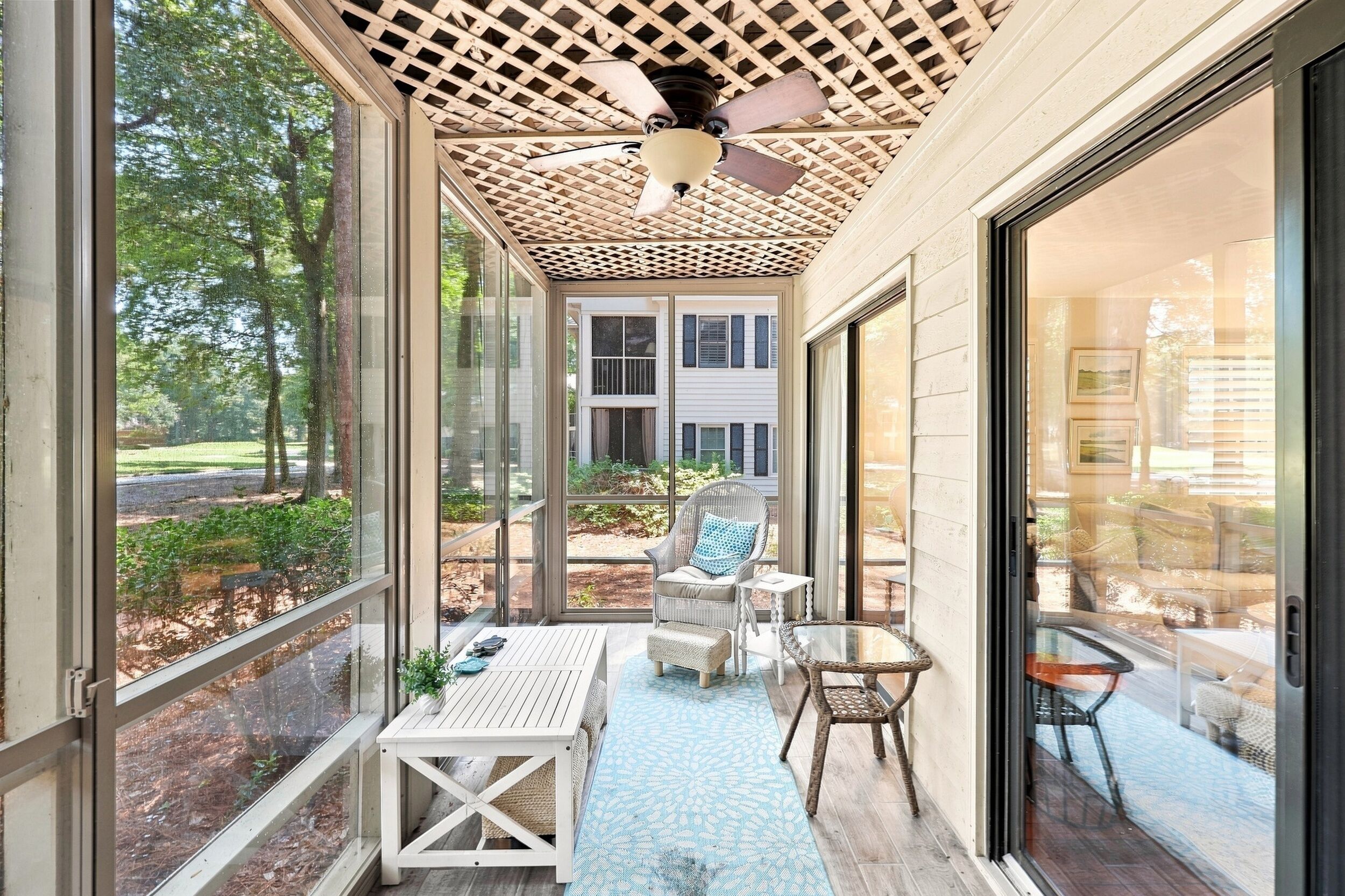 Une terrasse couverte avec un ventilateur de plafond, une table, des chaises et une vue sur le jardin arrière.