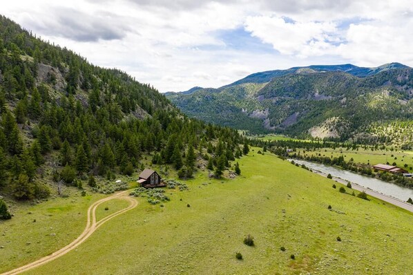 Paisaje rural con una casa, un río y montañas.