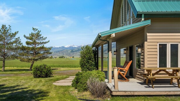 A wooden house with a covered porch, a picnic table, and a view of mountains. - Crow Cabin- Cozy Cabin with amazing views on 20 Acres in the Paradise Valley! (Livingston)