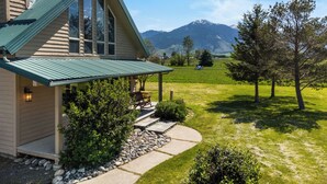 A house with a green roof, large windows, and a stone pathway leading to a porch. - Crow Cabin- Cozy Cabin with amazing views on 20 Acres in the Paradise Valley! (Livingston)