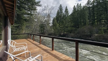 Enjoy the serene river views from this deck, surrounded by lush greenery and tall trees.