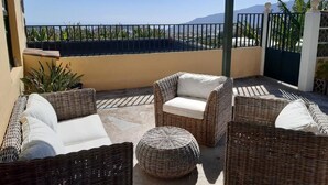 A covered outdoor seating area with wicker furniture and a view of the ocean. - PRIVATE RURAL HOUSE WITH POOL (Los Llanos)