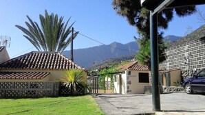 A residential street with houses, a parked car, and mountains in the background. - PRIVATE RURAL HOUSE WITH POOL (Los Llanos)