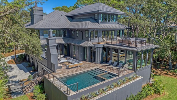 A modern house with a large deck, a swimming pool, and a covered outdoor area. - Ocean, golf and lagoon views, complete renovation luxury home (Kiawah Island)