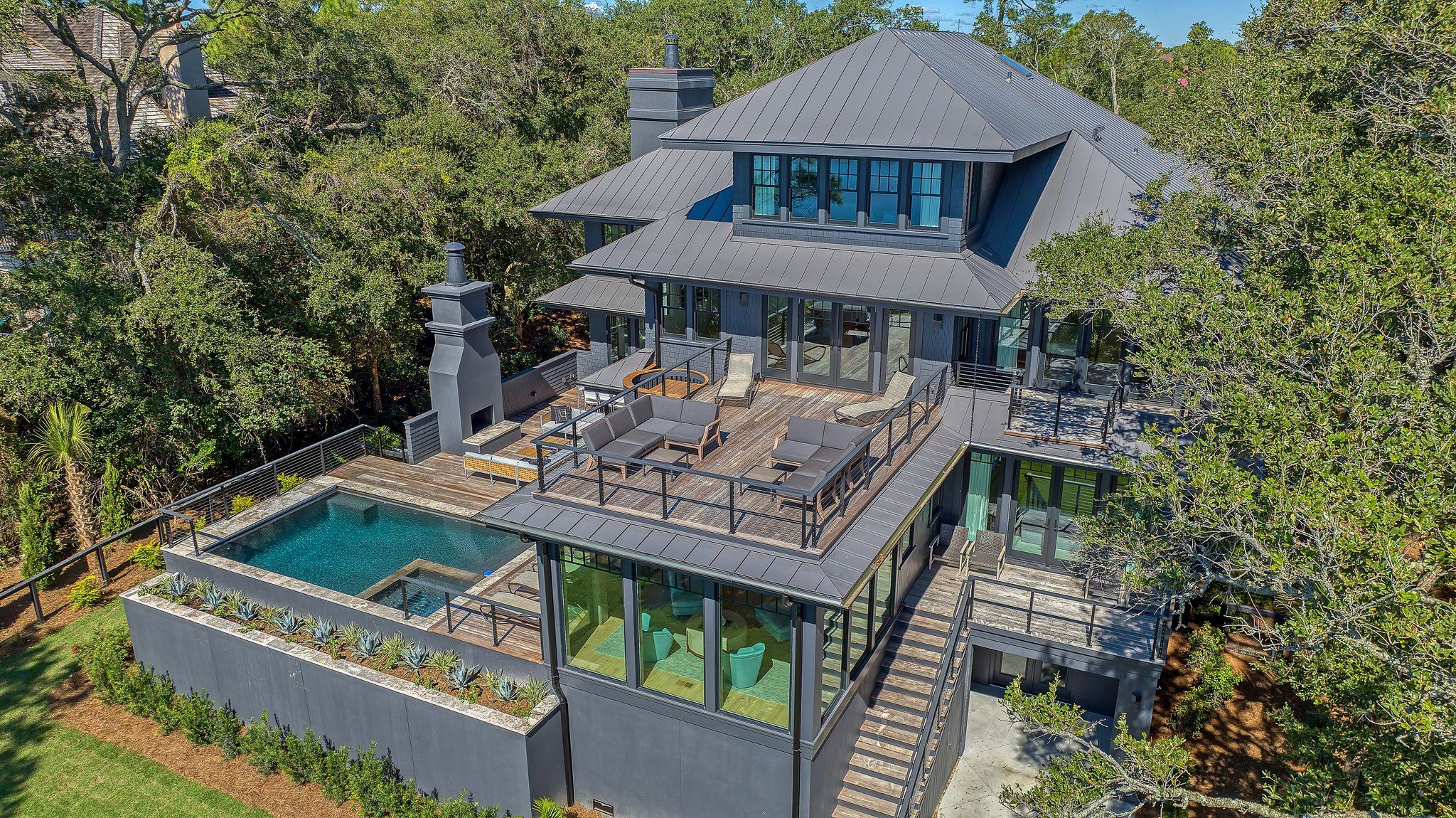 Una casa moderna con una terraza grande, una piscina y una chimenea.