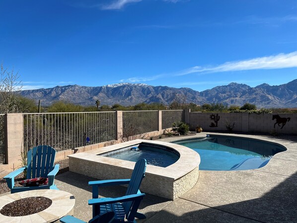 Ein Swimmingpool mit Bergblick, zwei Adirondack-Stühle und eine Kakteen-Wandmalerei.