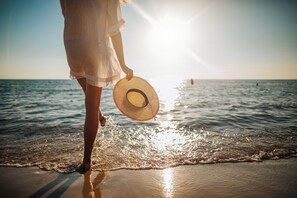 A person standing on a beach holding a straw hat, with the ocean and a clear sky in the background. - Private Pool And Gulf Views- Sugar Magnolia By Royal Destinations (Santa Rosa Beach)