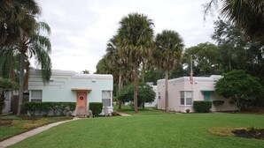 A residential area with two light-colored houses, each with a front porch and a small lawn.