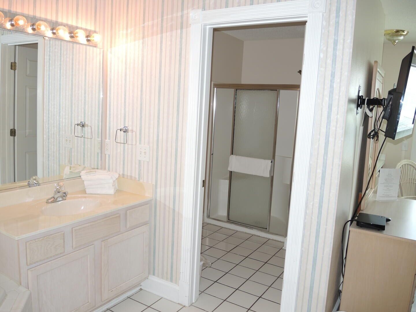 A bathroom with a large mirror, a sink, and a shower area.
