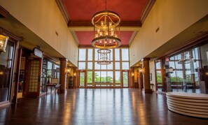 Eine großzügige Lobby mit hoher Decke, großen Fenstern und einem zentralen Kronleuchter.